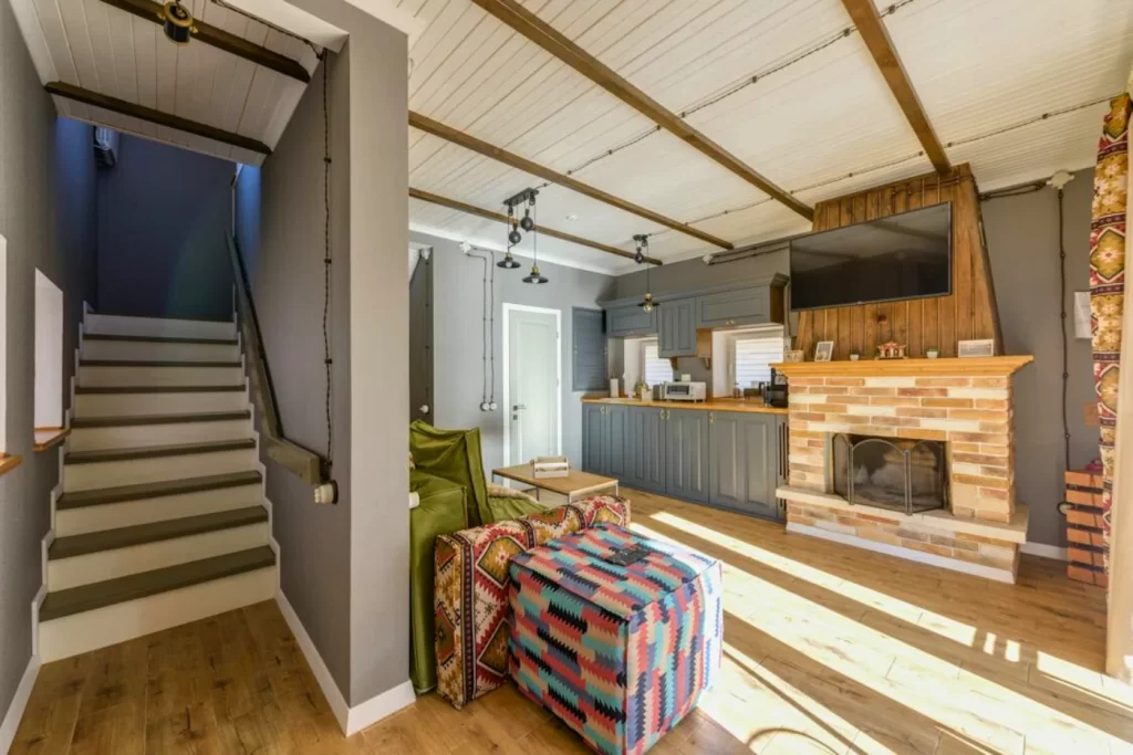 Home remodeling Rustic living room with brick fireplace, exposed beam ceiling, cozy seating, and natural wood flooring for a warm, inviting atmosphere.