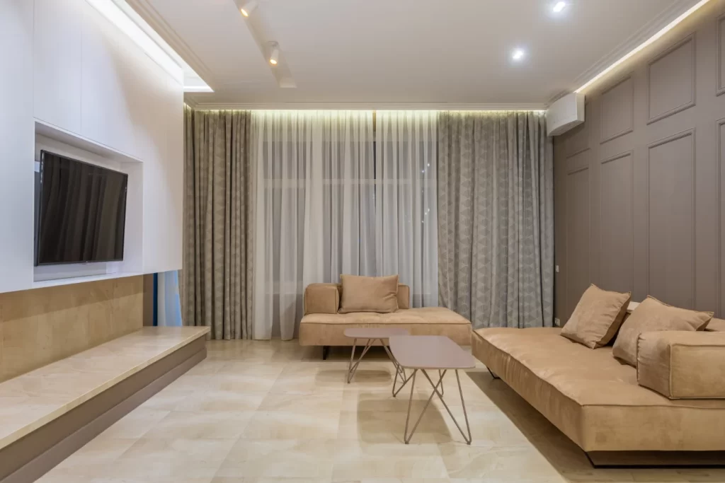 Home remodeling Minimalist living room with neutral tones, modern decor, cozy sectional sofa, and ambient lighting for a serene and stylish atmosphere.