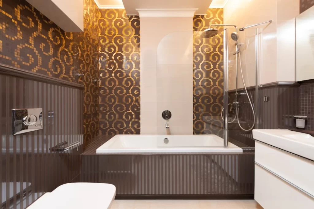 Luxurious bathroom remodeling with mosaic accent wall, modern bathtub, glass shower partition, and sleek fixtures for an elegant design.