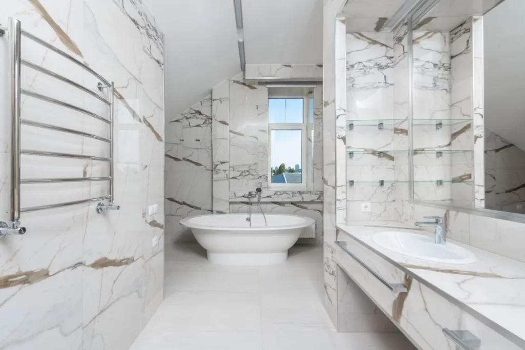 Luxurious marble bathroom remodeling design with freestanding bathtub, double vanity, large mirrors, and stainless steel towel rack.
